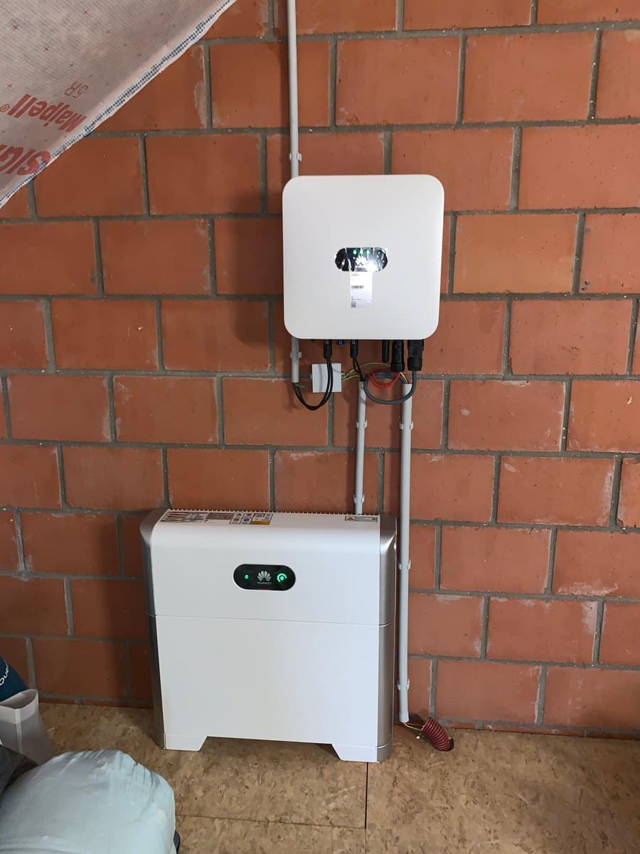 Omvormer en thuisbatterij tegen een bakstenen kelderwand