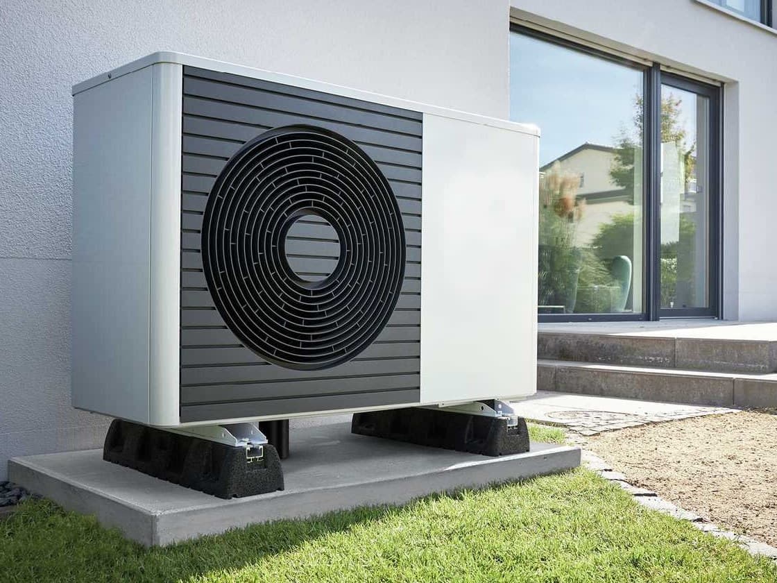 Buitenunit van een warmtepomp in een tuin